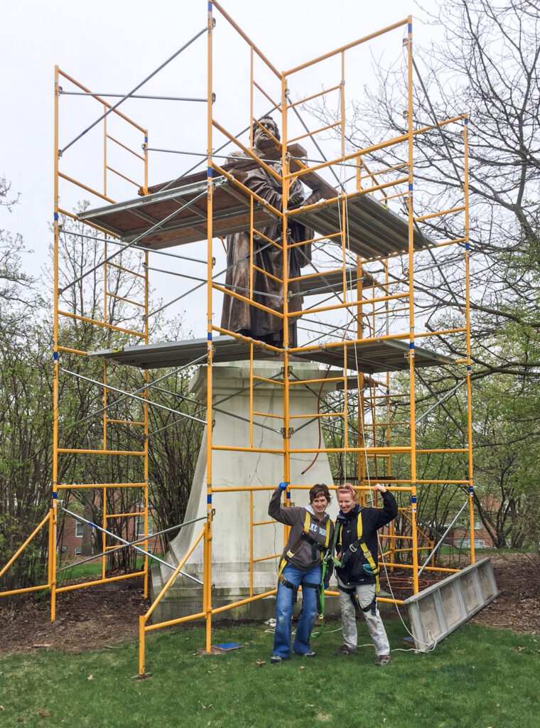 Fellows pose with a sculpture with scaffolding surrounding it