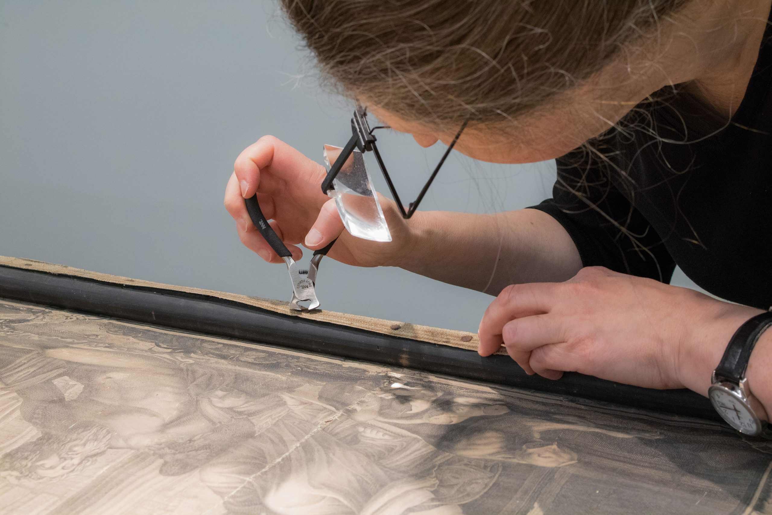 A practitioner carefully removes a canvas from a frame