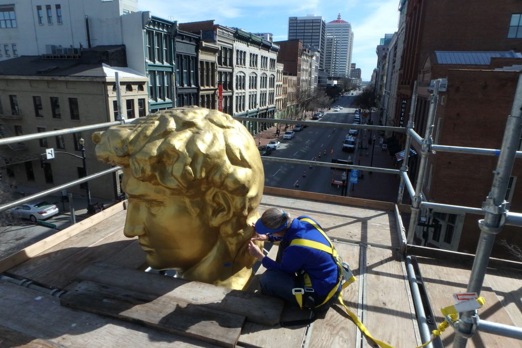 Performing restoration on a large gilt head from a statue