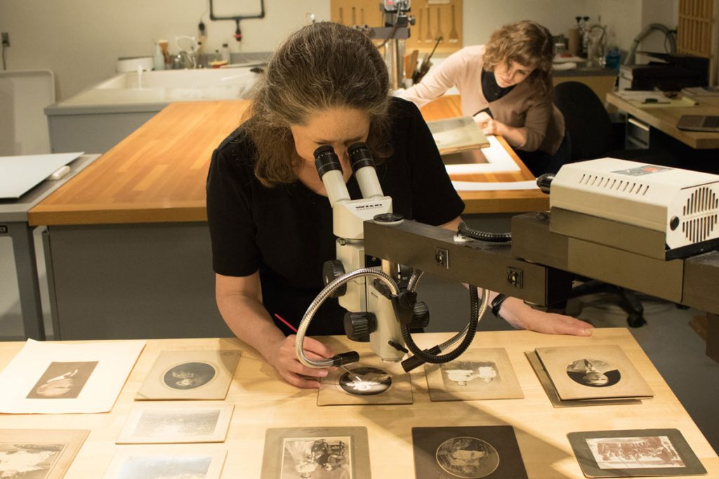 A MACC employee examining work under a microscope